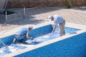 two workers resurfacing a pool in the winter