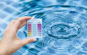 pool maintenance technician checking for water chemistry issues during spring pool opening
